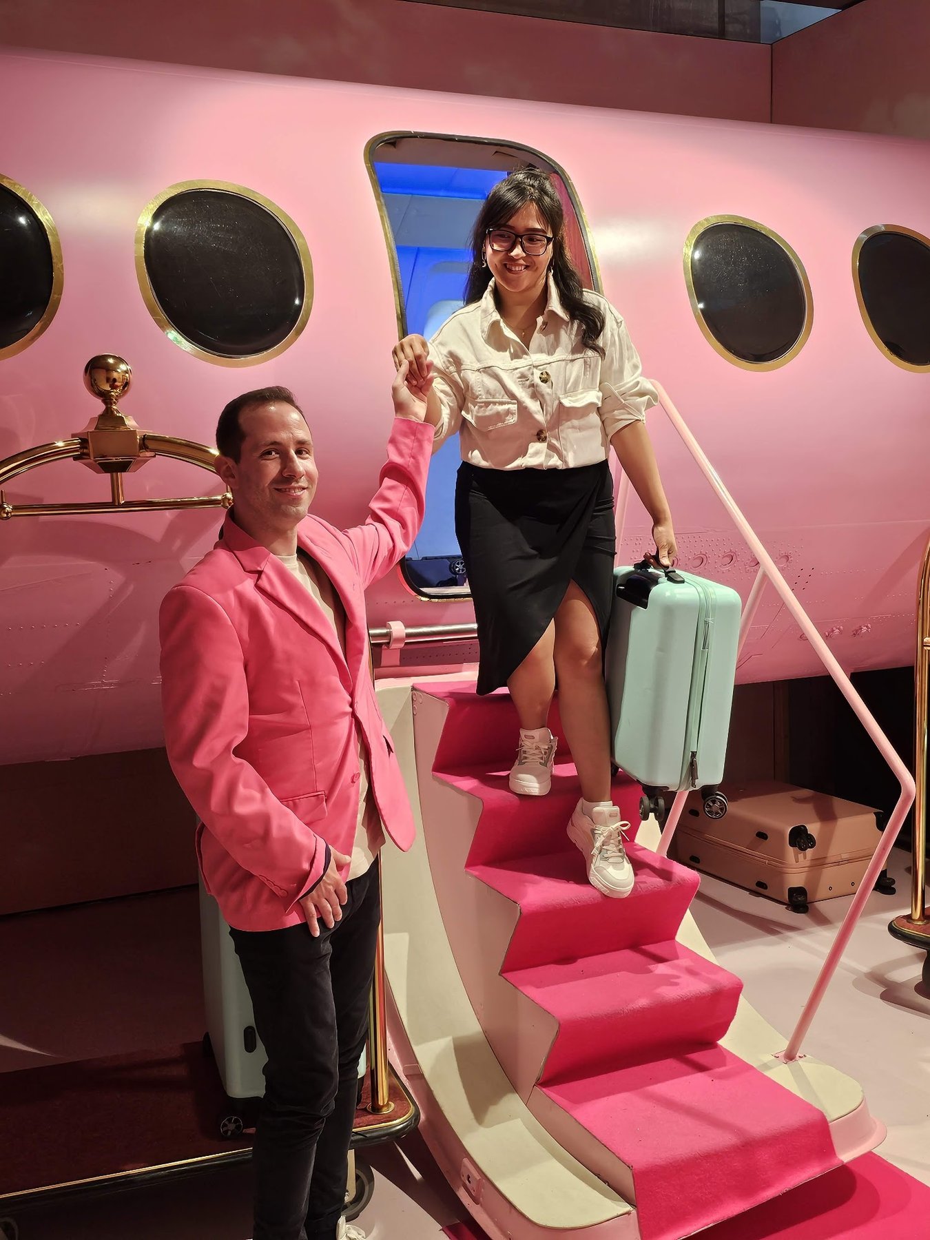 Chern stepping down the hot-pink airplane stairs with her mint suitcase while Javier takes her hand